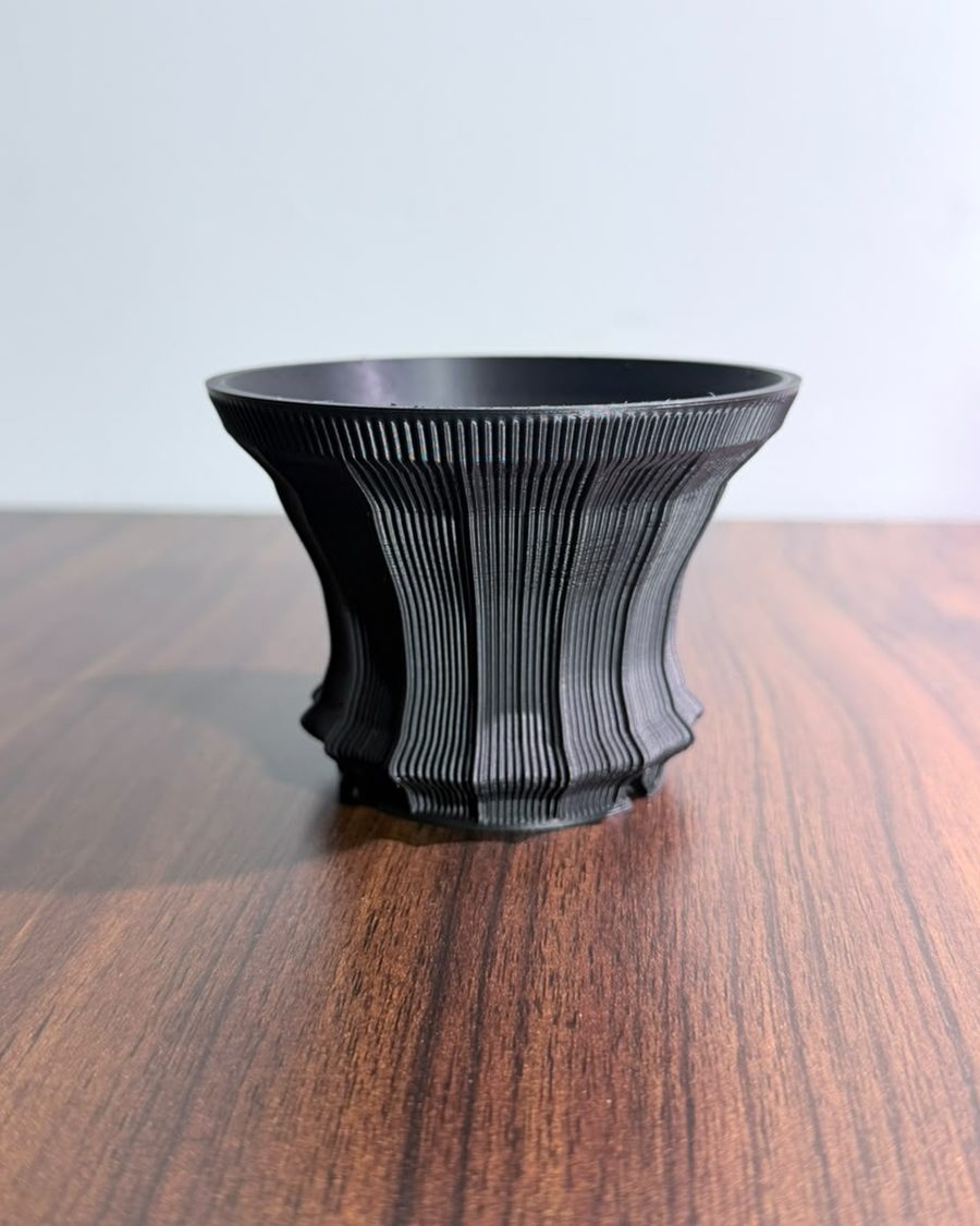 Black 3D-printed planter with fine vertical reeds and a flared rim